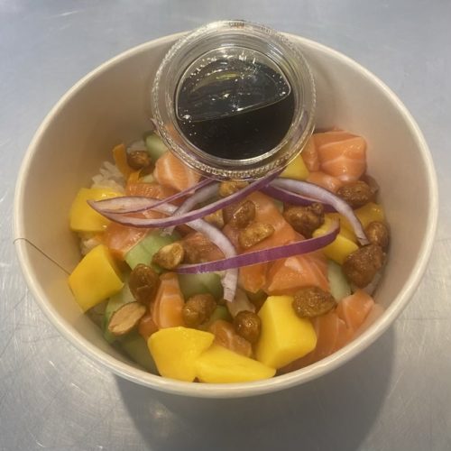 pokebowl saumon, carottes, concombre, mangue, saumon cru, oignons rouges, dans une boite à emporter