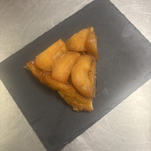 tarte tatin avec des pommes caramélisées sur une assiettes en ardoise noire